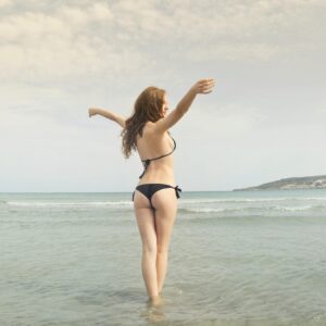 A young woman in a bikini enjoying the tranquil seaside at Mgarr, Malta, during summer.